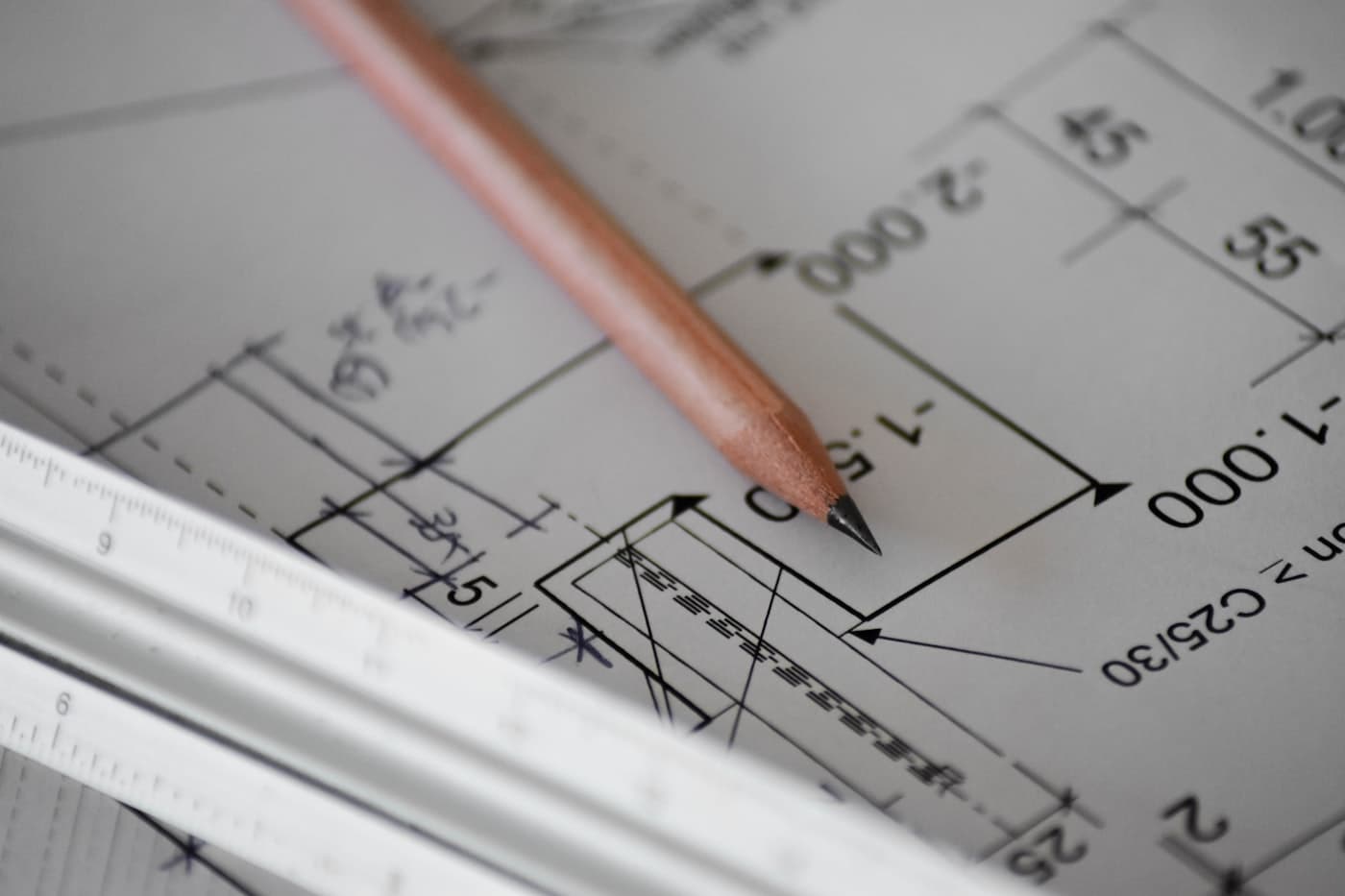 A pencil resting on a sheet of white drafting paper, marked with faint construction lines.